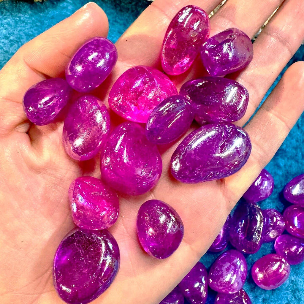 Hand holding purple gemstones with a blue background