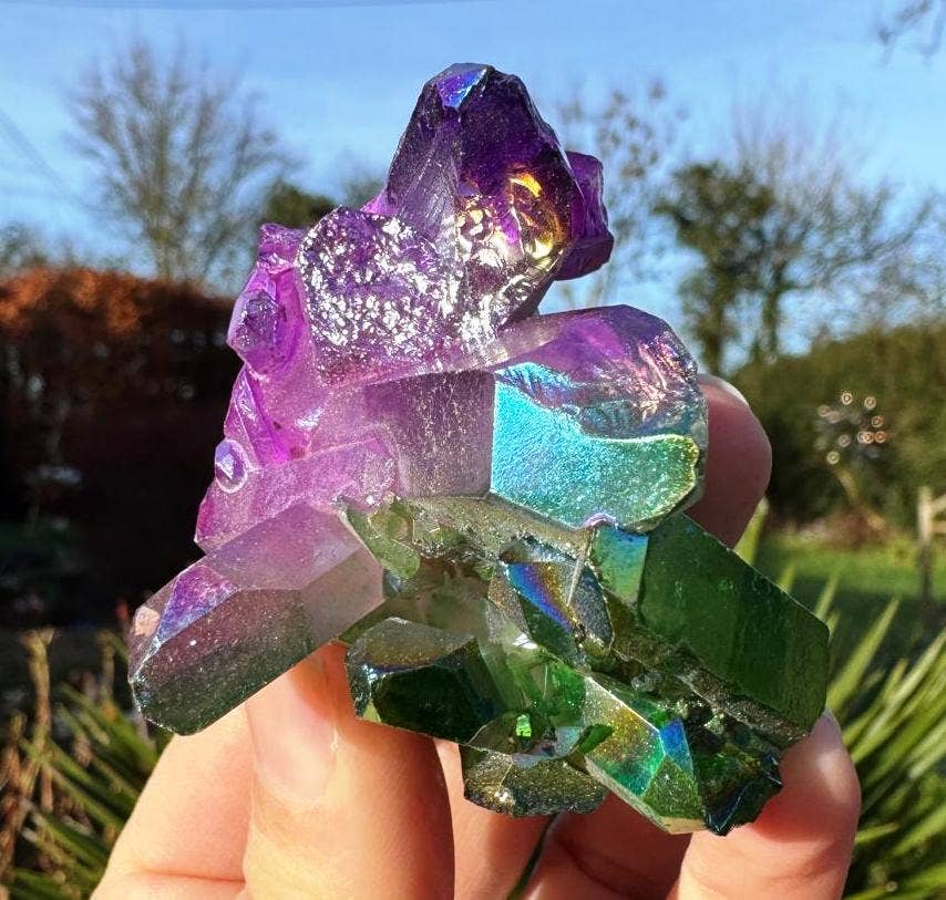 Colorful crystal held in a hand with a blurred natural background