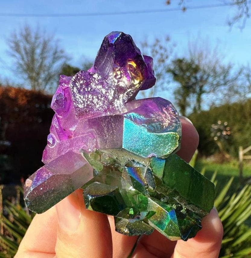 Colorful crystal held in a hand with a blurred outdoor background