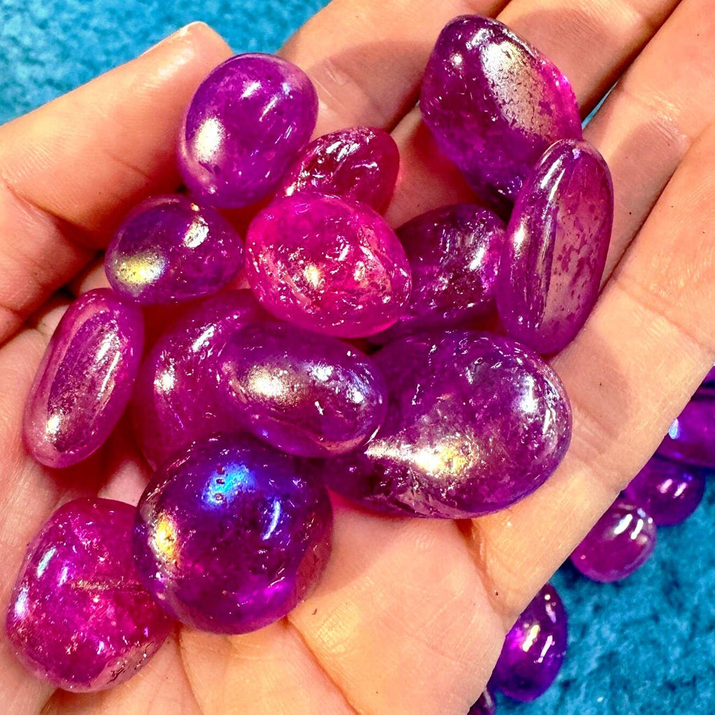 Hand holding purple and pink glittery stones against a blue textured background