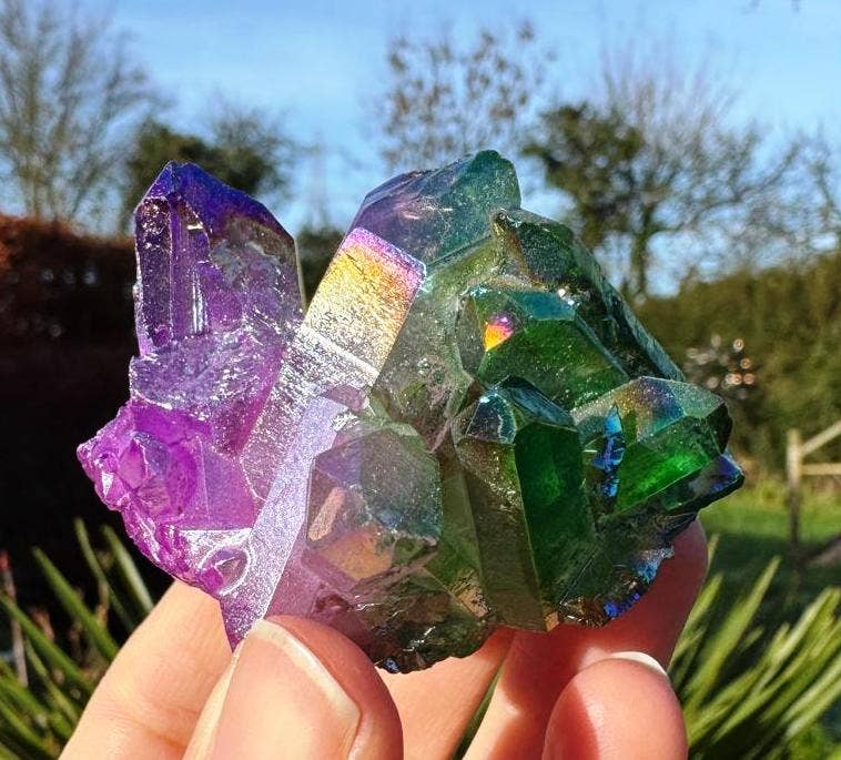 Colorful crystal formation held in hand with natural background