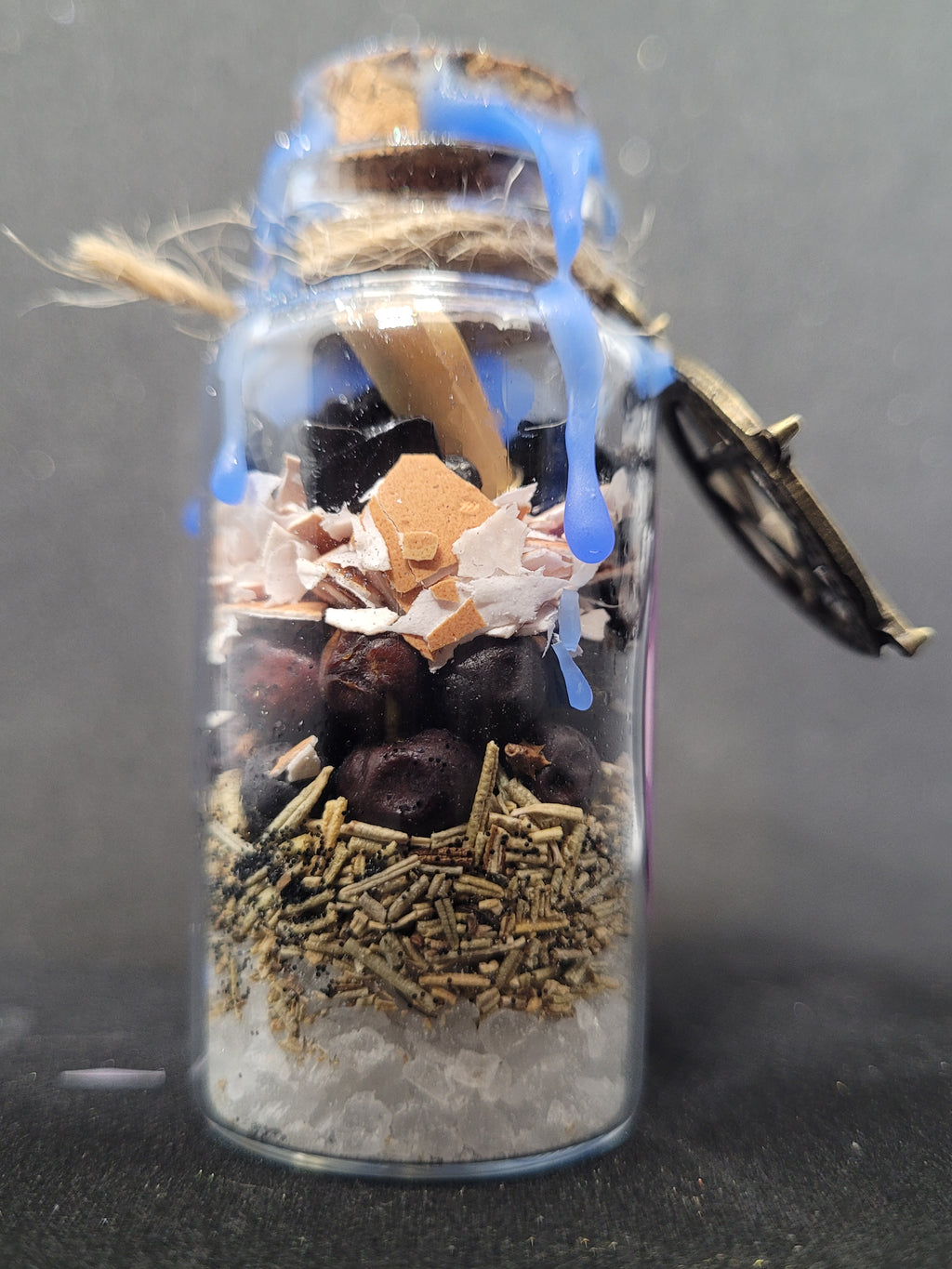 Small Spell-bottle with various items inside on a dark background